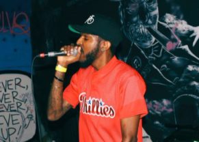 Picture of Drell on stage holding microphone