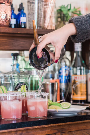 Bar attendant pouring cocktail drinks in a glass cup