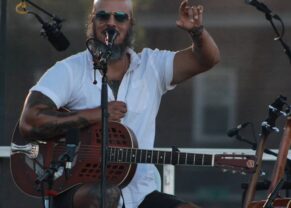 Picture Samuel James performing with a microphone and a guitar