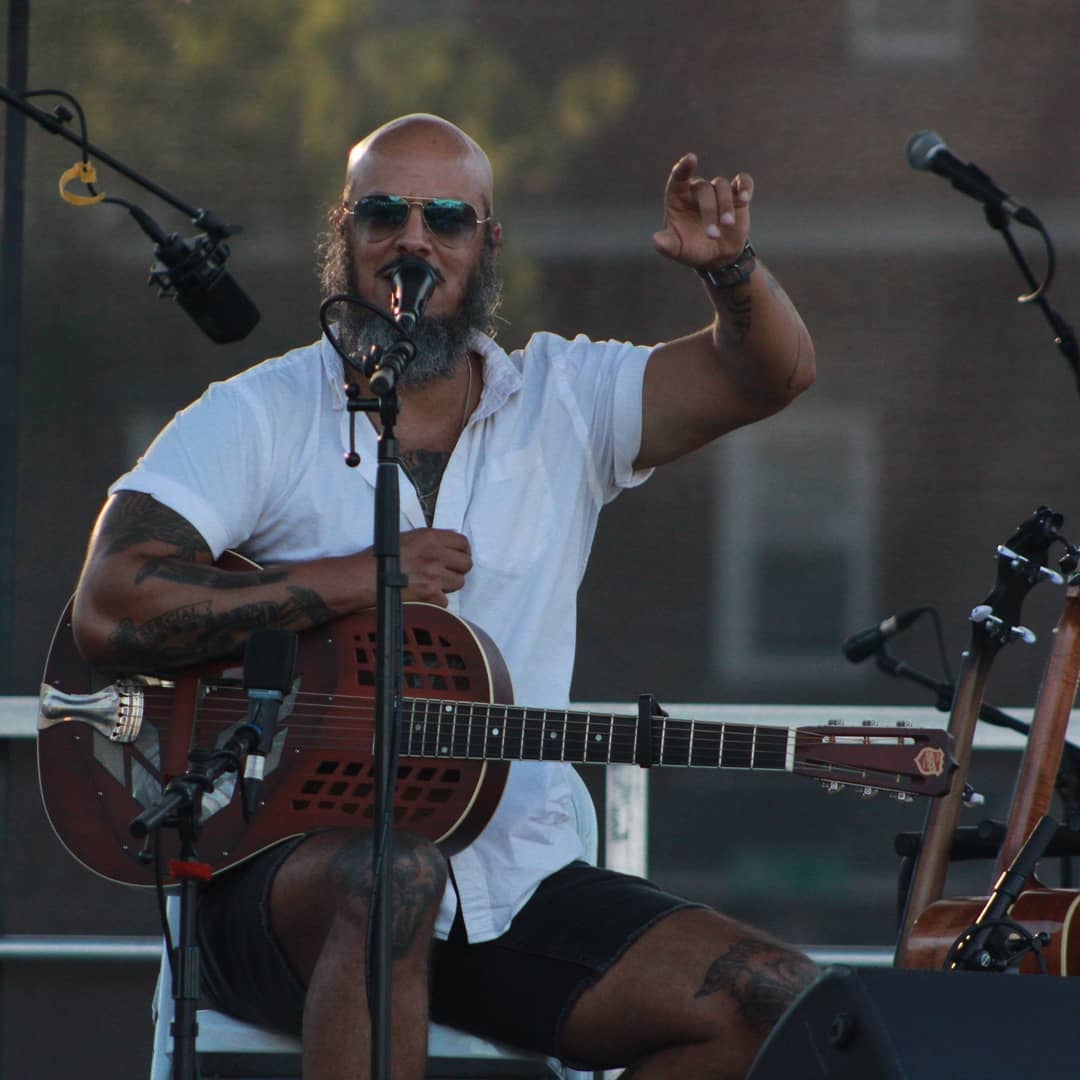 Picture Samuel James performing with a microphone and a guitar